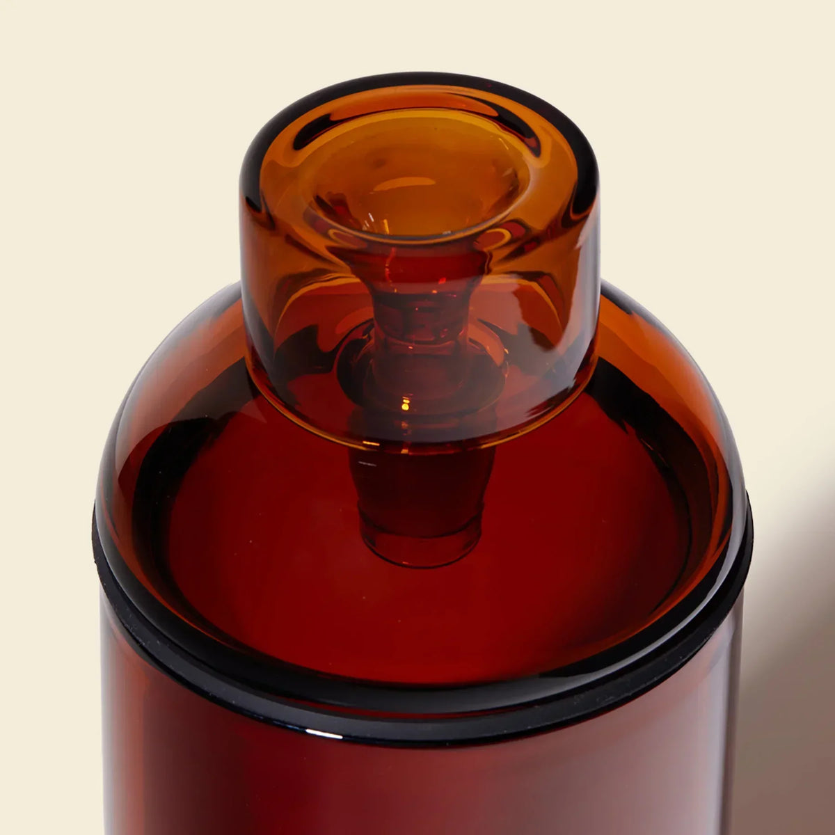 Close-up of amber glass gravity bong top with modern, clean design against light background.