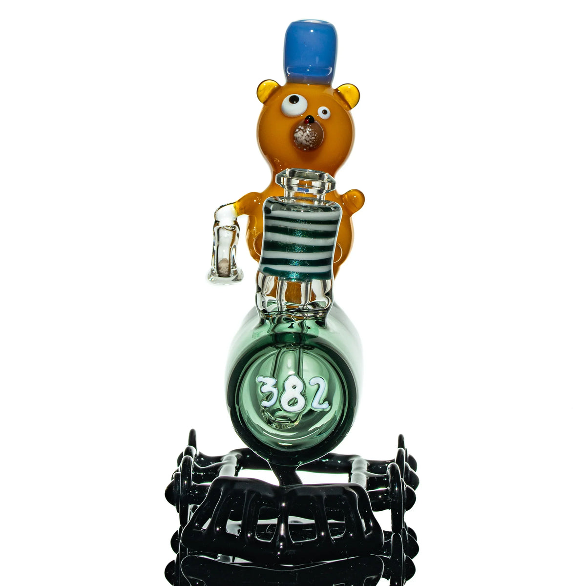 Heady glass pipe shaped like a train with a whimsical bear figure and blue hat, number 382.