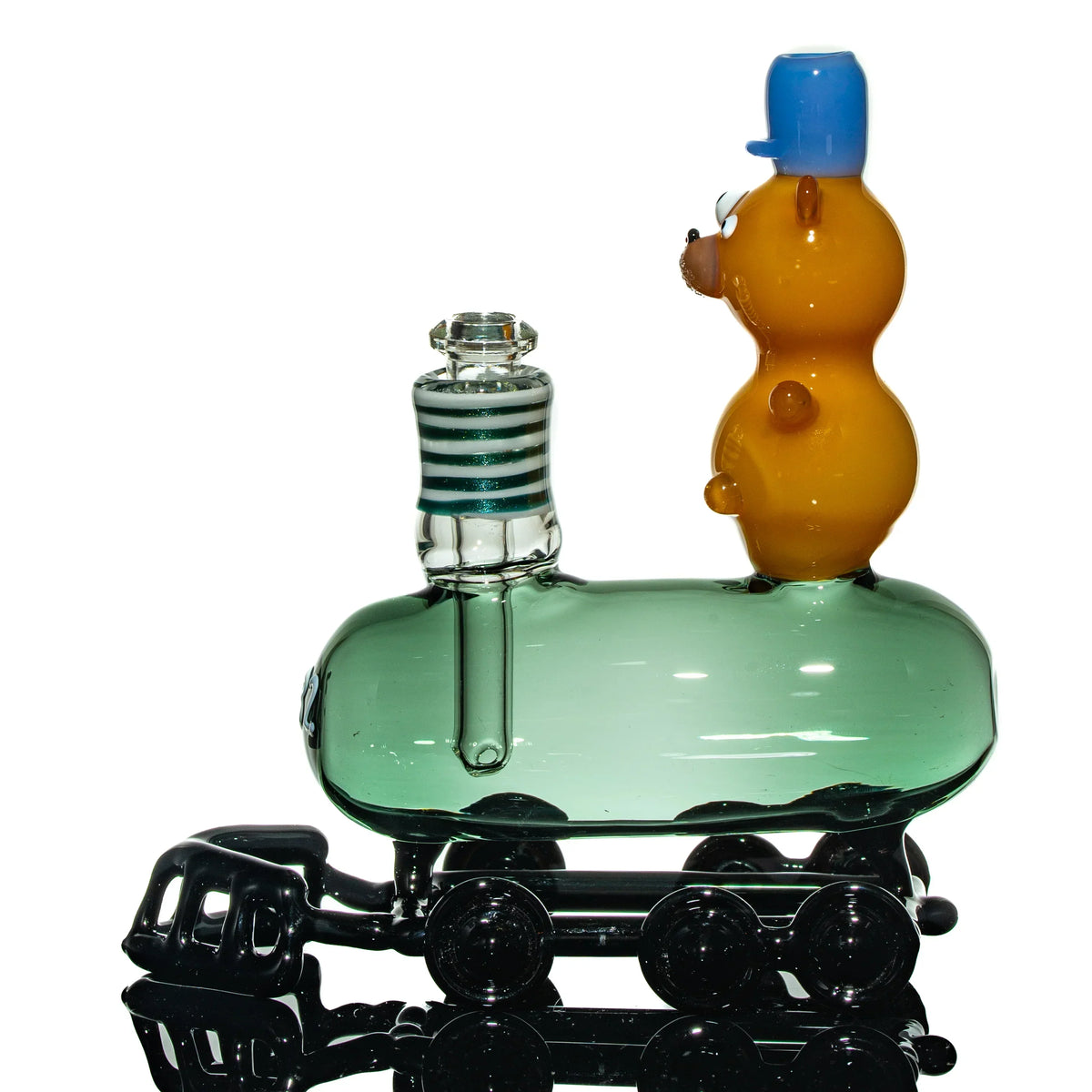 Hand-blown glass pipe shaped like a train with an orange bear figure wearing a blue hat.