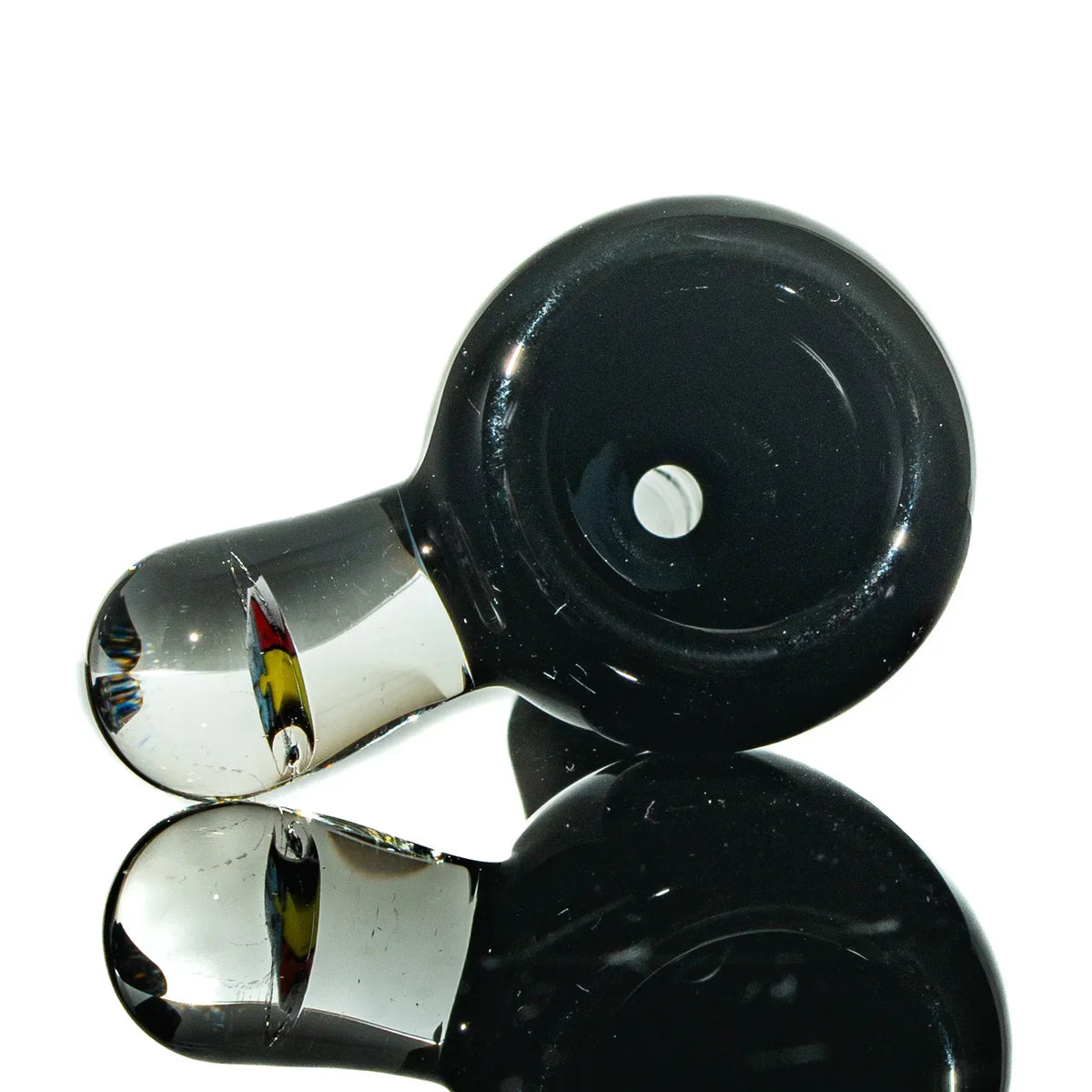 Black glass hand pipe with clear glass mouthpiece on a reflective surface