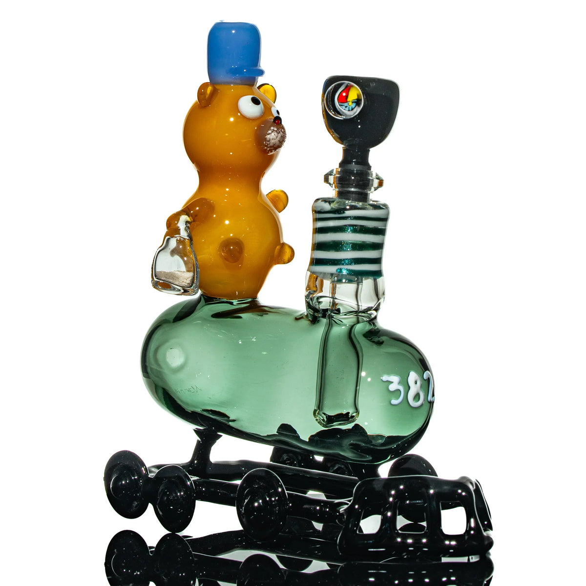 Artisan glass water pipe shaped like a train with a cartoon bear figure on top