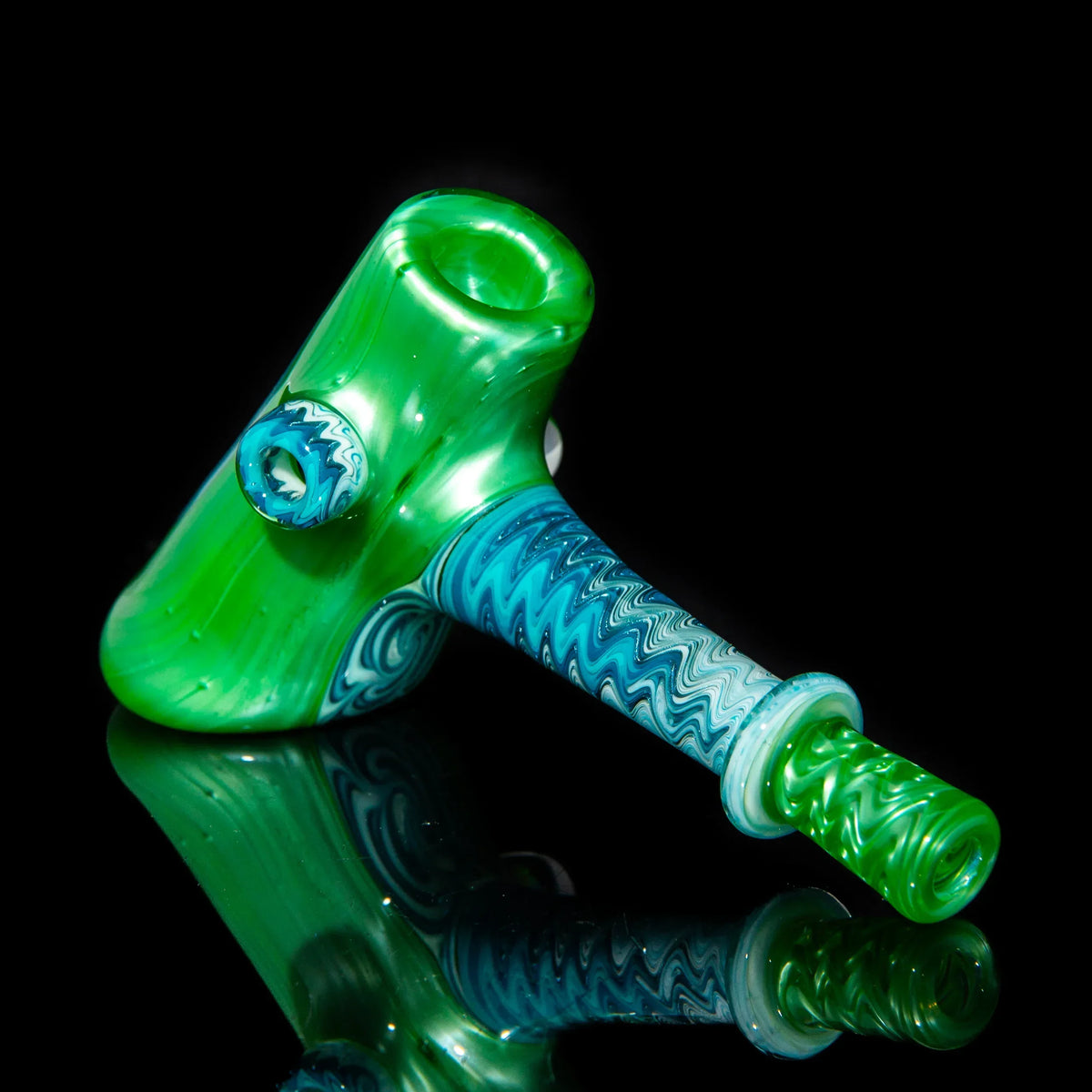Green and blue glass hammer pipe with intricate linework on a black background.