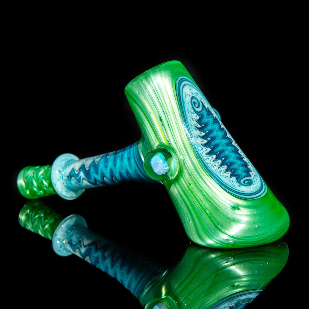 Green and blue glass hammer pipe with intricate linework on black background