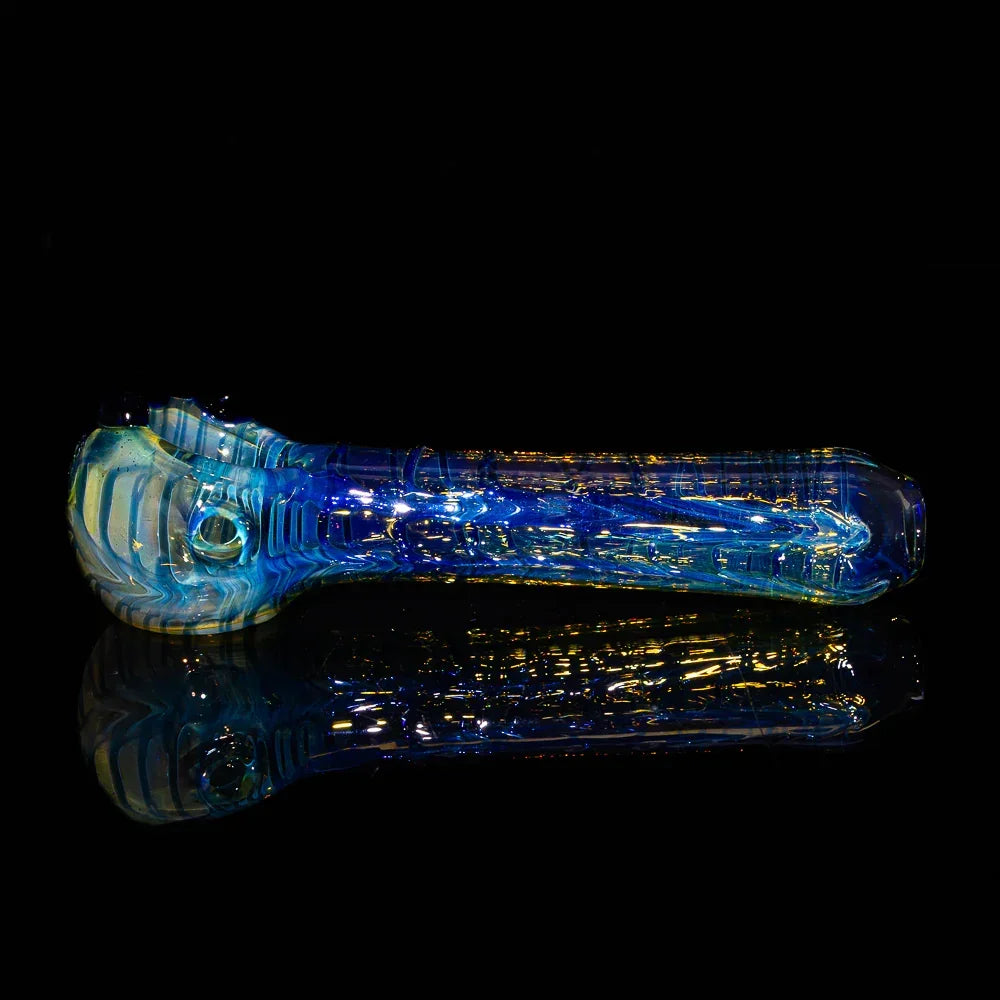 Blue fume wrapped glass spoon pipe with intricate raked design on black background