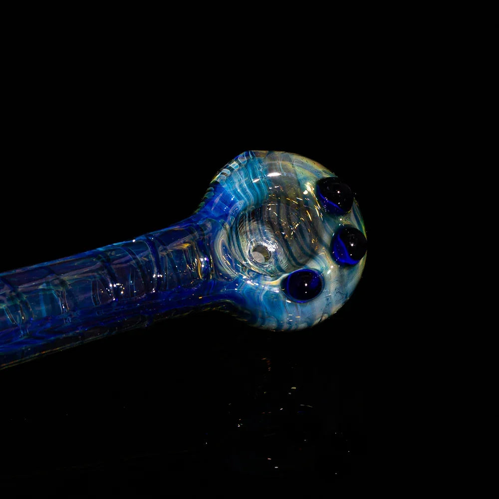 Blue fumed glass hand pipe with decorative marbles on a black background