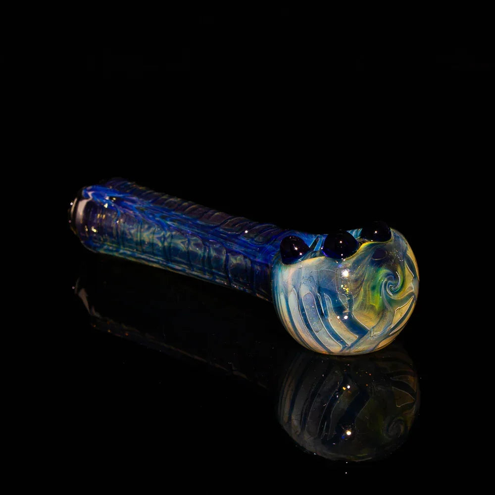 Handcrafted blue and yellow glass spoon pipe with fume wrap and rake accents on black background.