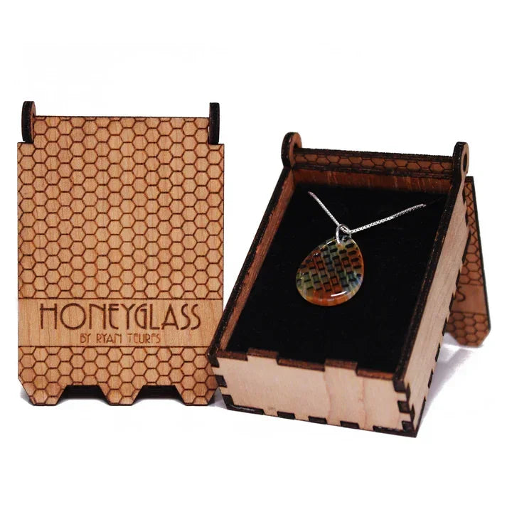 Teardrop honeycomb glass pendant necklace in a wooden box with honeycomb pattern.