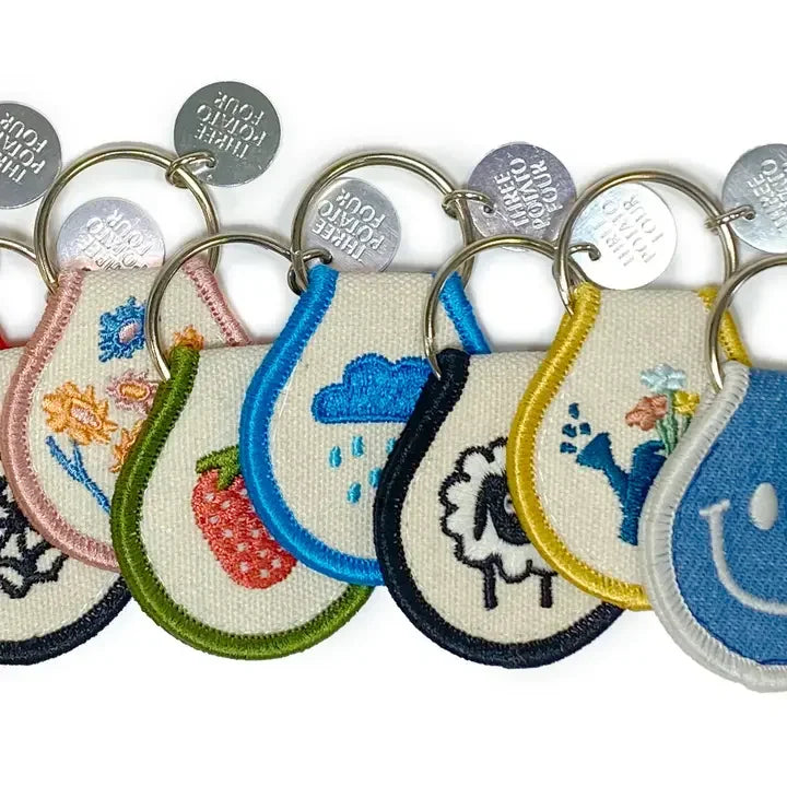 Embroidered patch keychains with colorful designs like flowers, strawberry, cloud, and sheep.