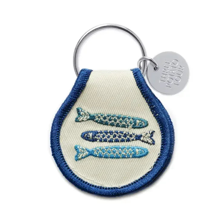 Embroidered tinned fish keychain with blue border and metal ring, novelty accessory