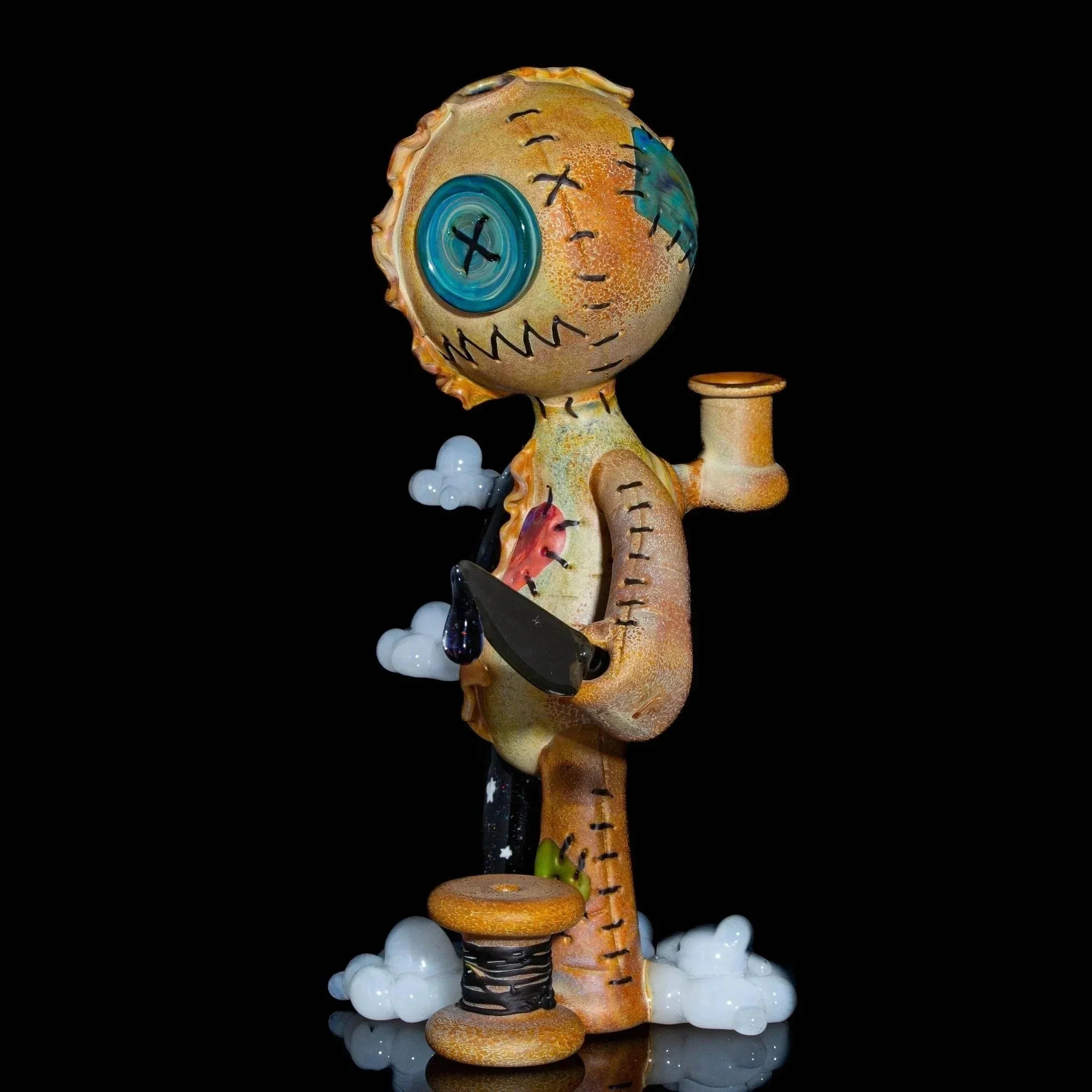 Handcrafted glass art doll-inspired dab rig with button eyes, stitching, and a cleaver on black background