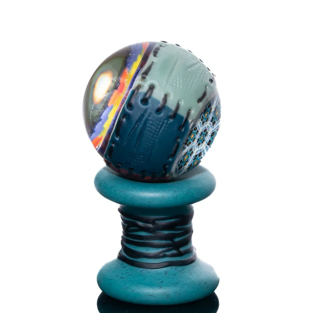 Colorful glass marble with quilted pattern on a teal spool stand, heady glass accessory