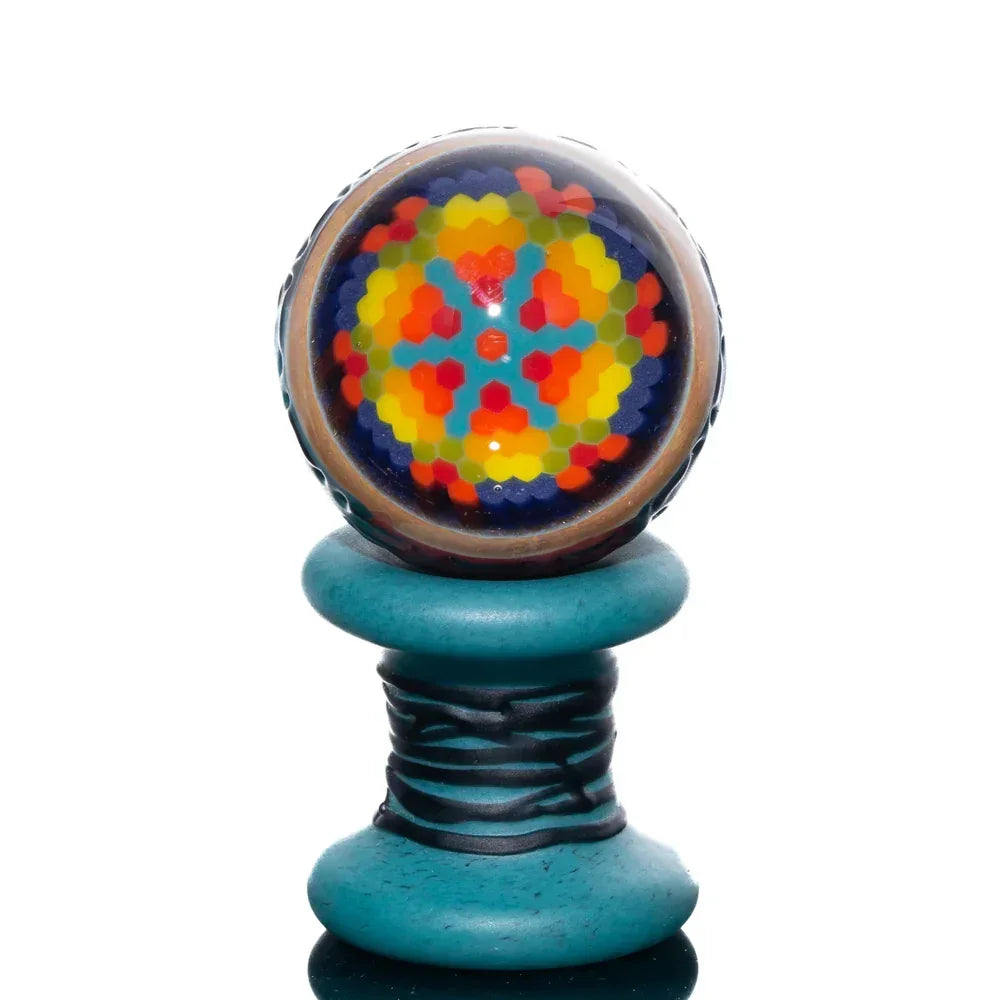 Colorful glass marble carb cap with quilted pattern on a turquoise spool stand