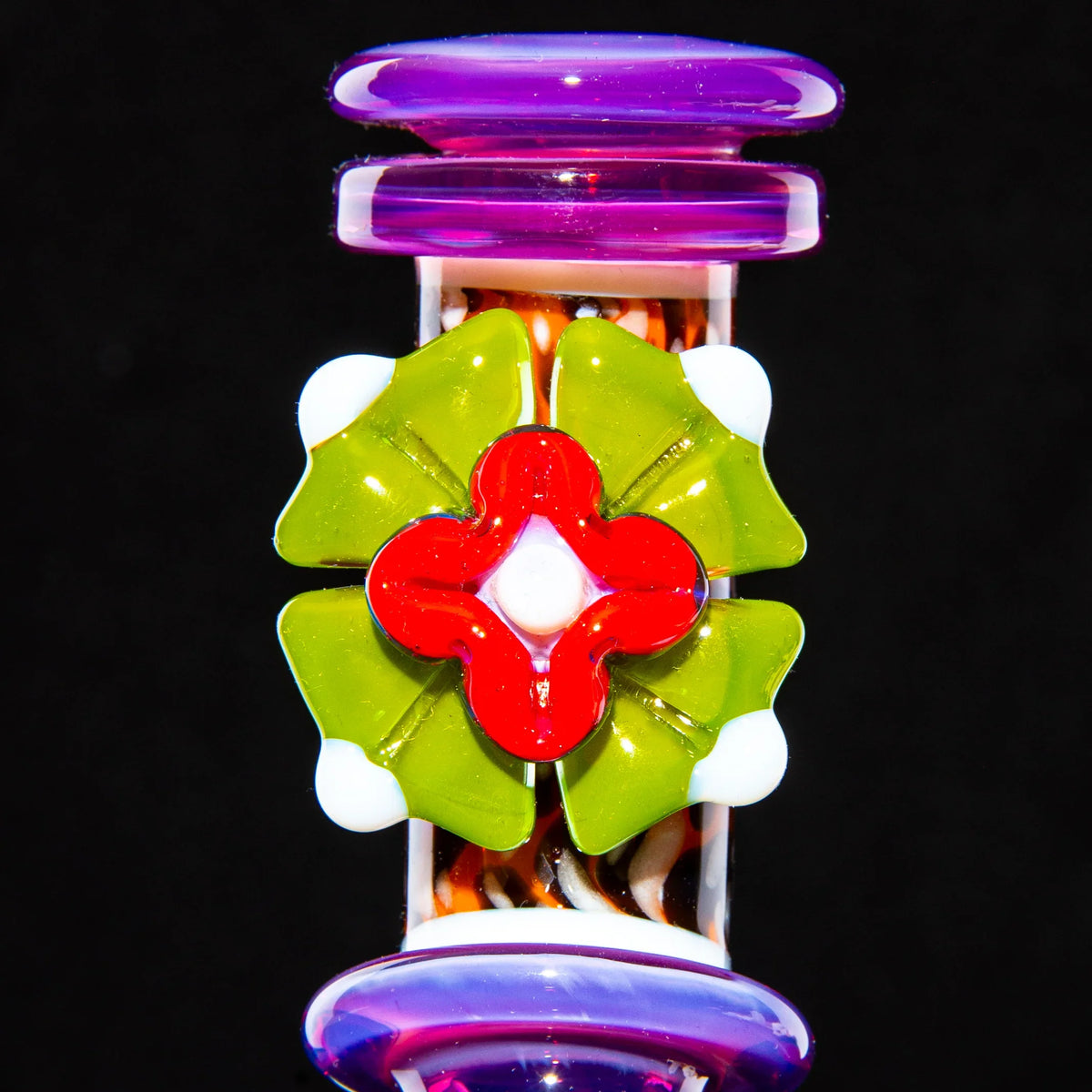 Colorful glass mini tube with green, red, and white floral design on a black background