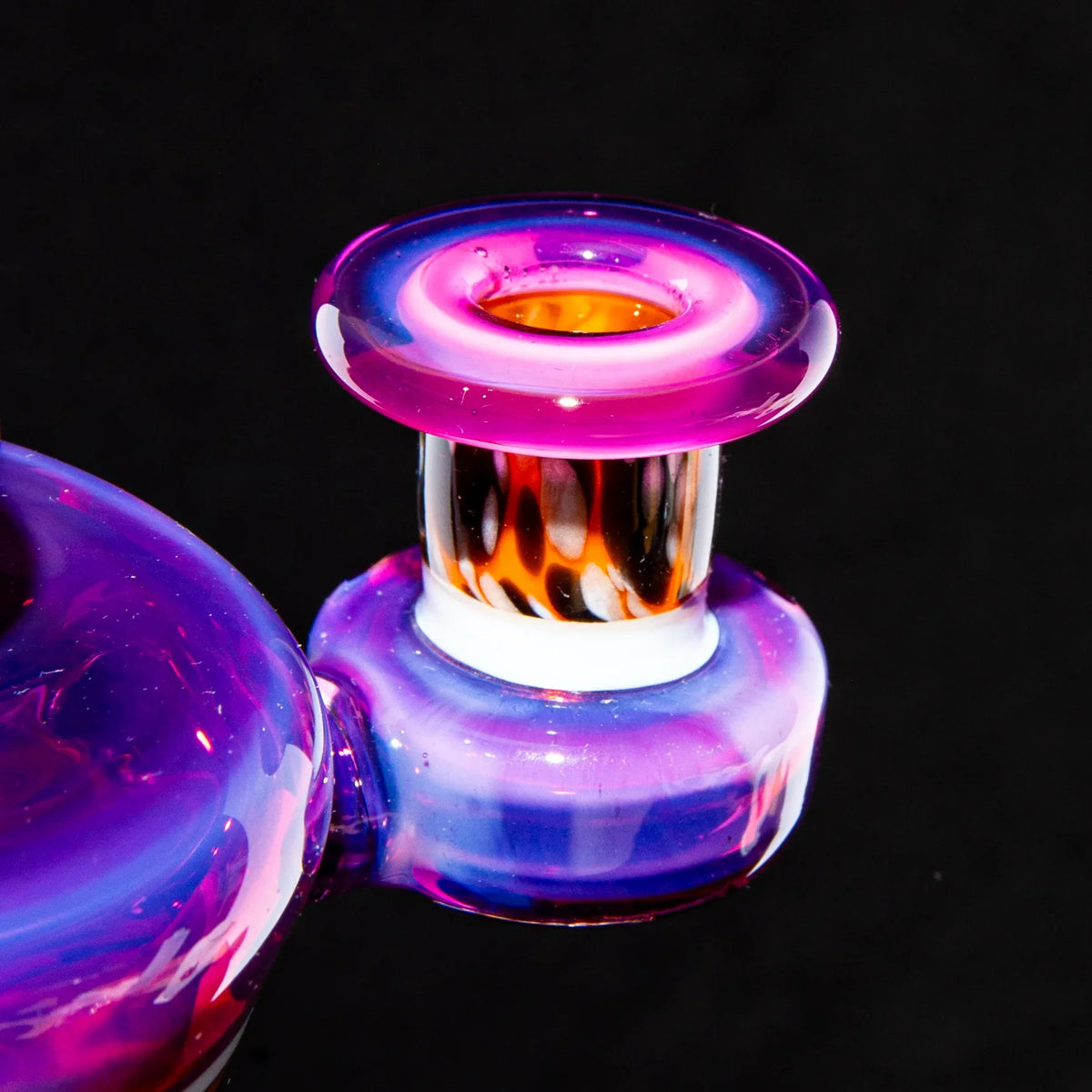 Colorful mini glass water pipe with vibrant pink and purple accents against a black background.