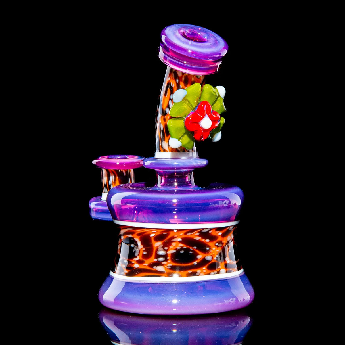 Colorful mini glass water pipe with purple, orange, and floral accents on a black background