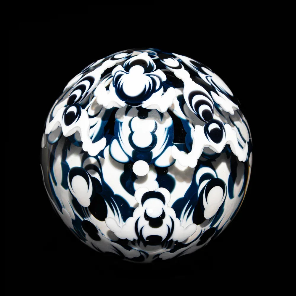 Intricate black and white patterned glass art orb on a black background