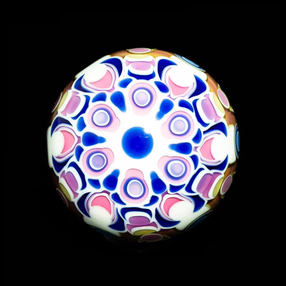Colorful glass marble with intricate blue, pink, and white mandala pattern on black background