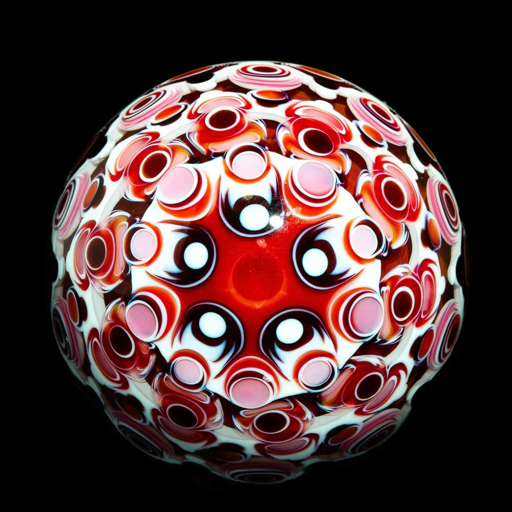 Heady glass marble with intricate red, white, and pink dot pattern on black background