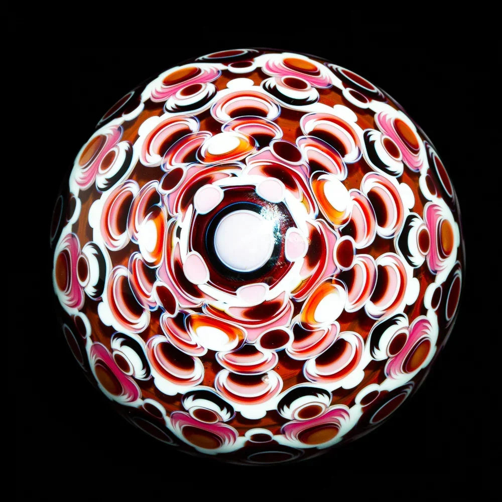 Colorful heady glass marble with intricate red, white, and pink patterns on black background