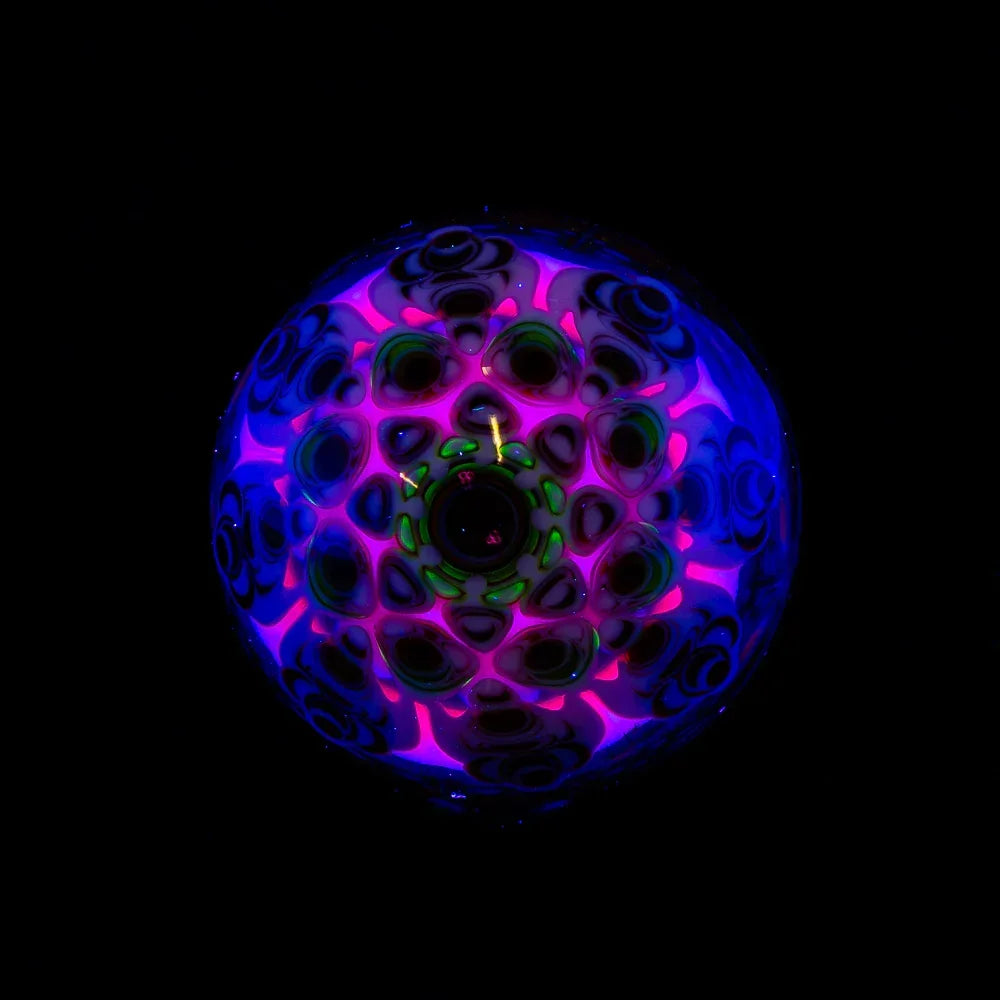 Colorful UV-reactive glass art piece with intricate patterns and neon details on black background