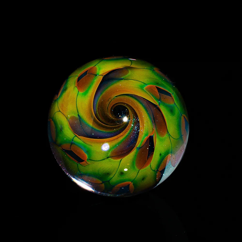 Colorful glass marble with green, orange, and blue spiral design on black background