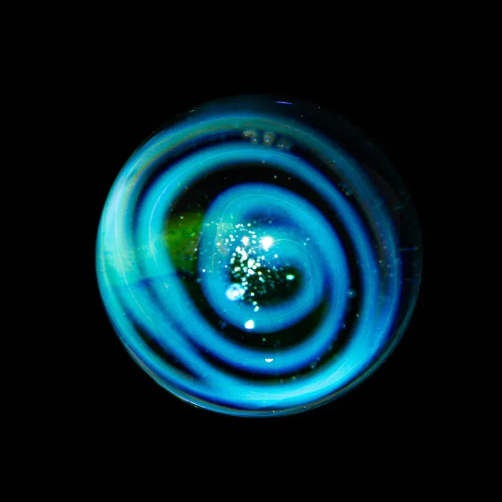 Blue glass marble with spiral design and stardust accents on a black background