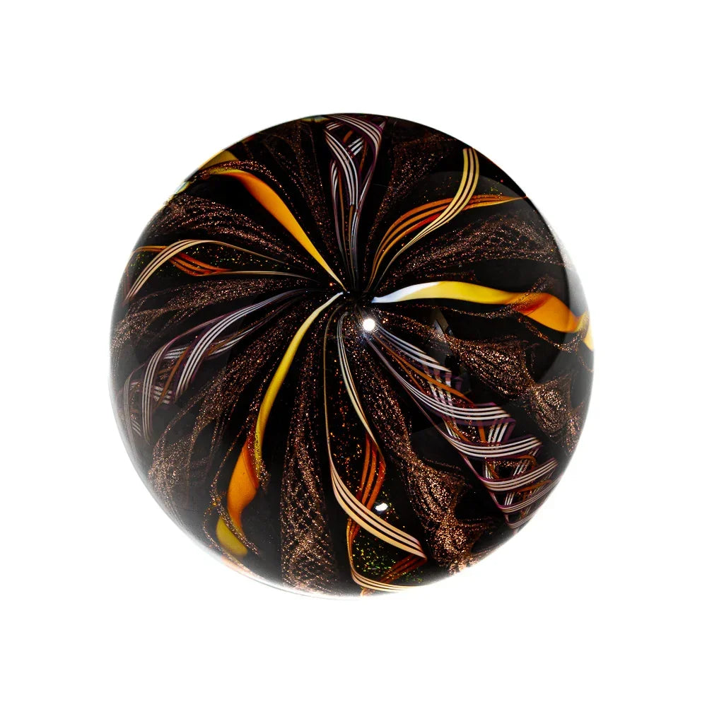 Handcrafted glass marble with swirling gold, amber, and black patterns on a white background