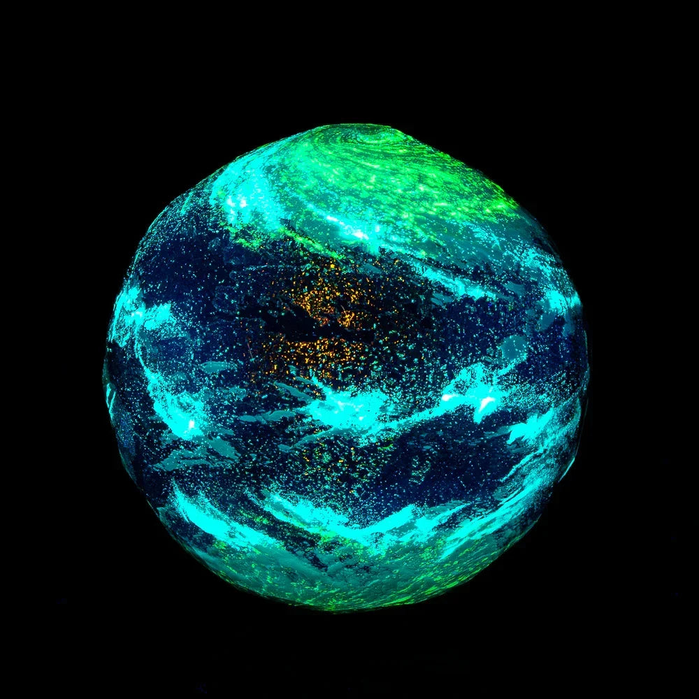 Faceted New Earth marble with glowing blue, green, and gold patterns on a black background