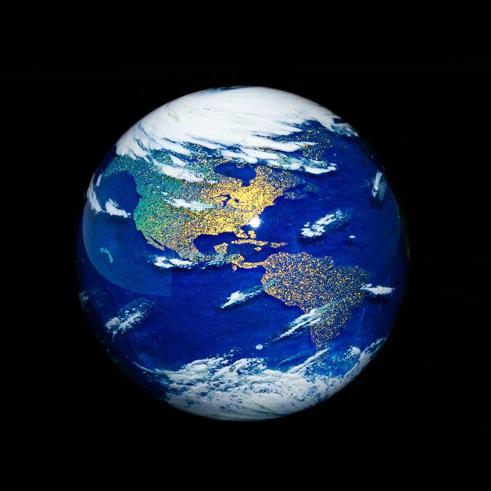 Handmade glass marble with glittery Earth design, featuring continents and deep blue oceans