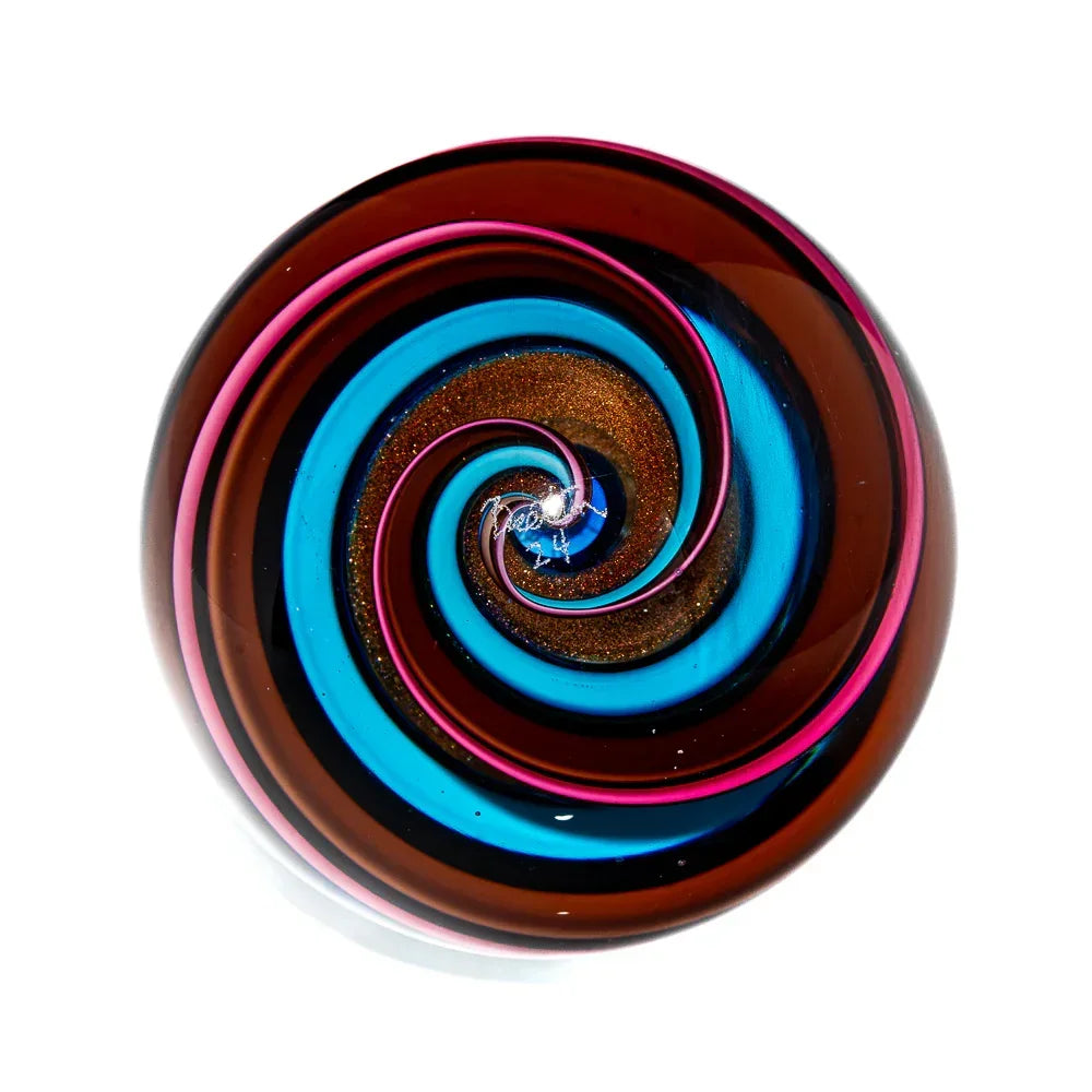 Handcrafted glass marble with blue, pink, and gold spiral ribbon design on white background