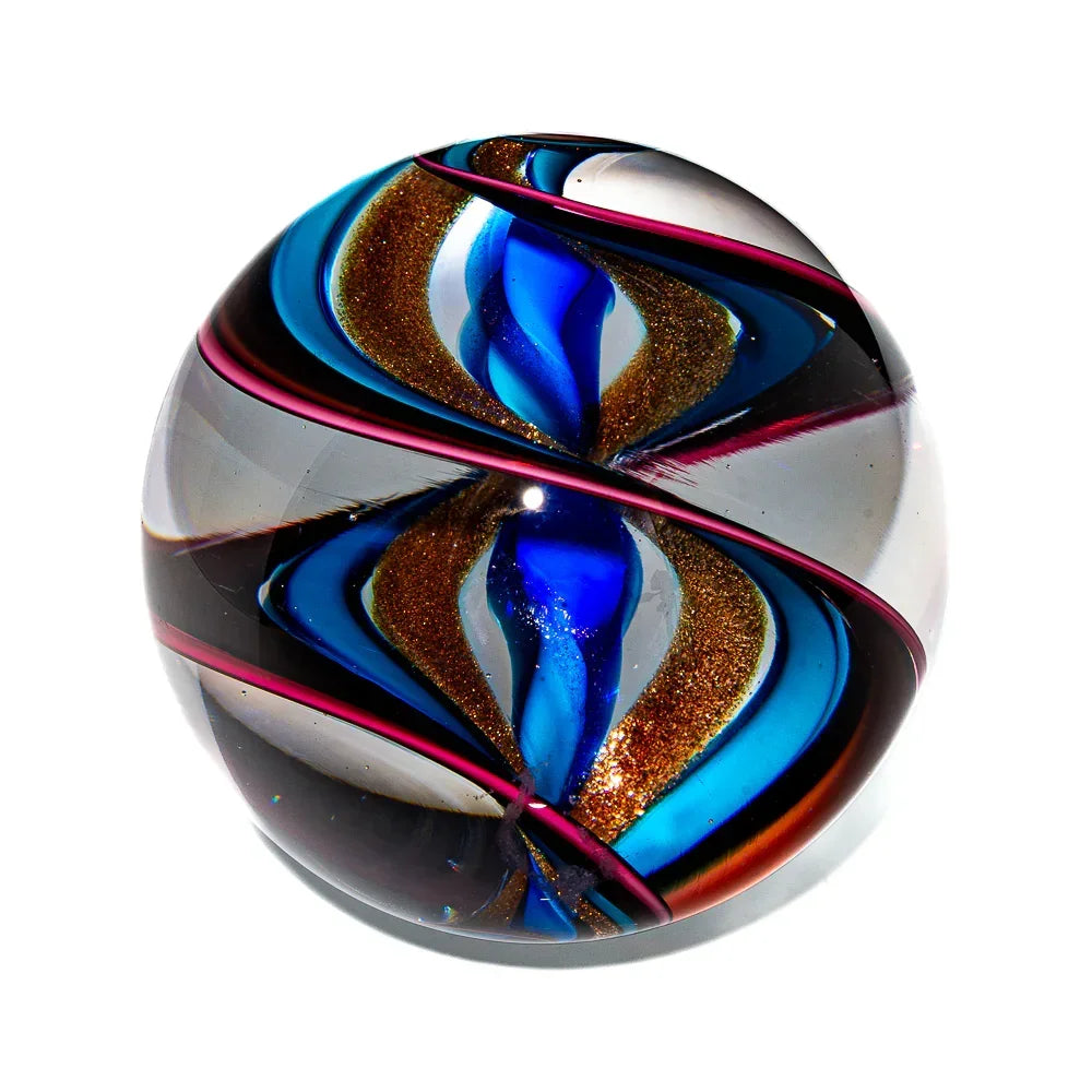 Handcrafted glass marble with blue, gold, and pink swirling ribbon design on white background