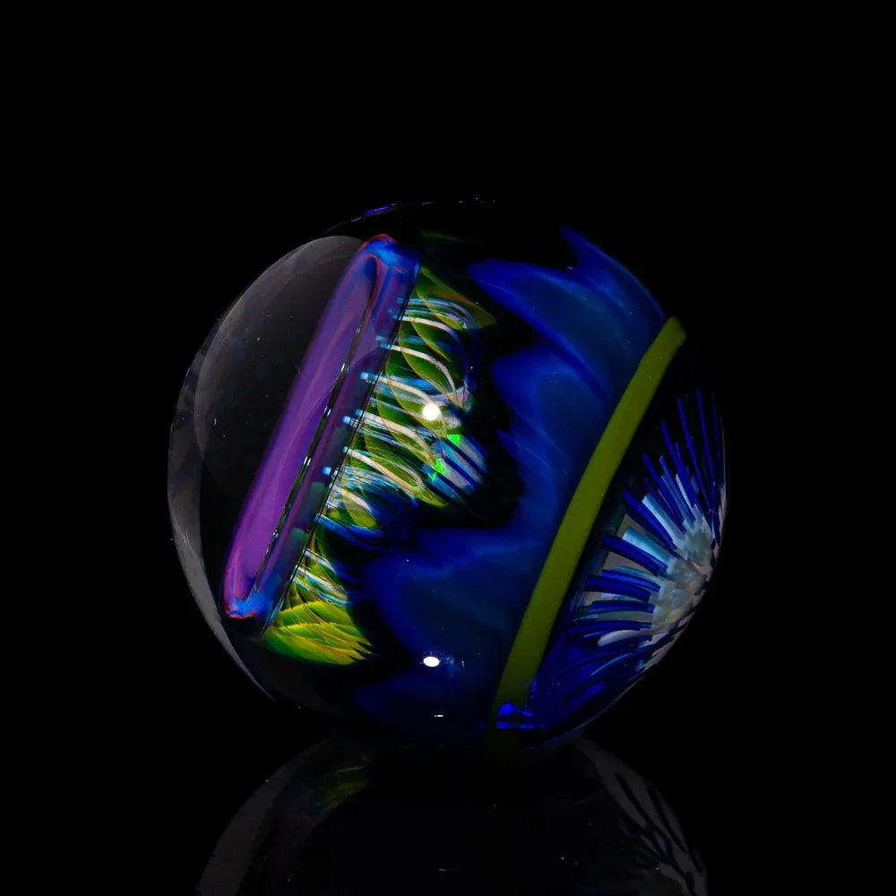 Art glass marble with vibrant blue, green, and purple swirling patterns on black background