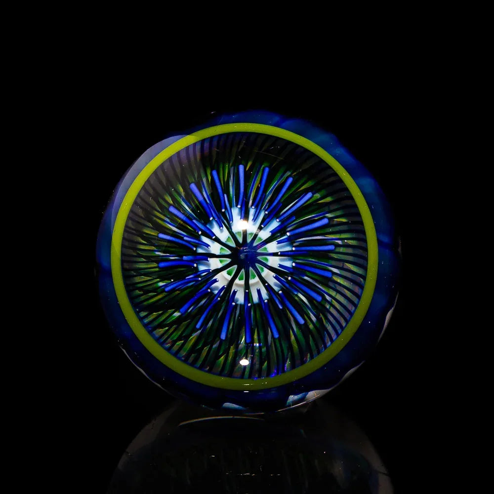 Colorful heady glass marble with blue, green, and yellow intricate pattern on black background