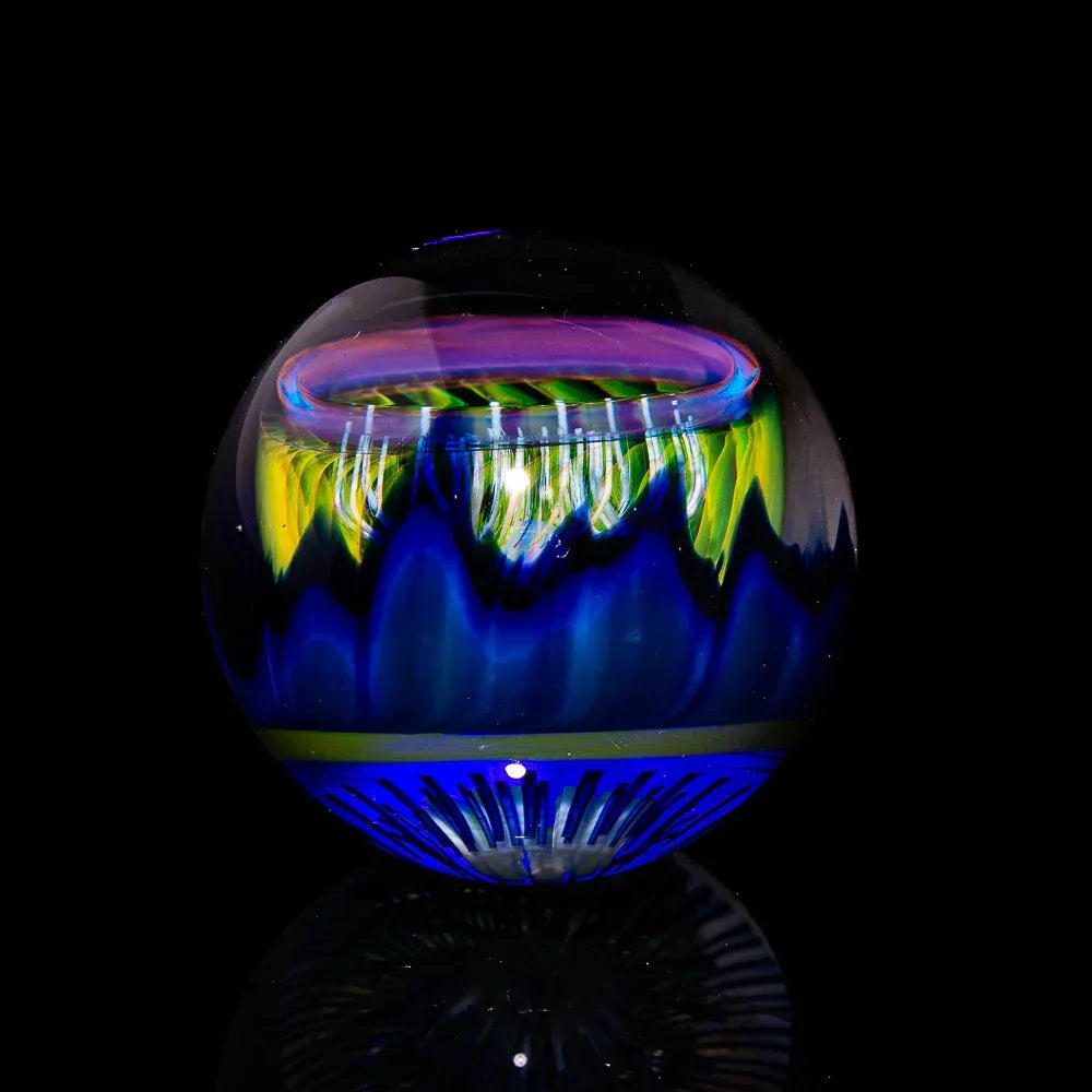 Colorful hand-blown glass orb with blue, yellow, and pink hues on a black background