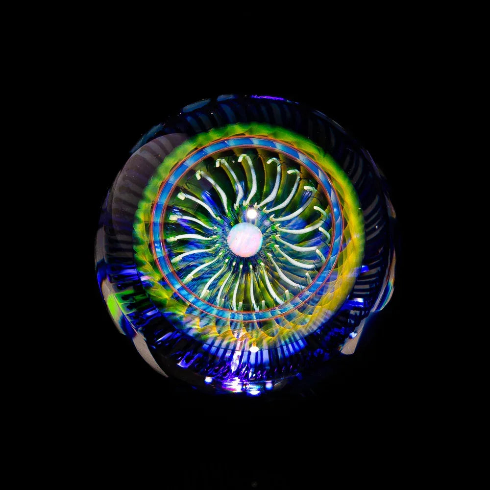 Hand-blown glass marble with intricate colorful patterns and spiral design, on black background.