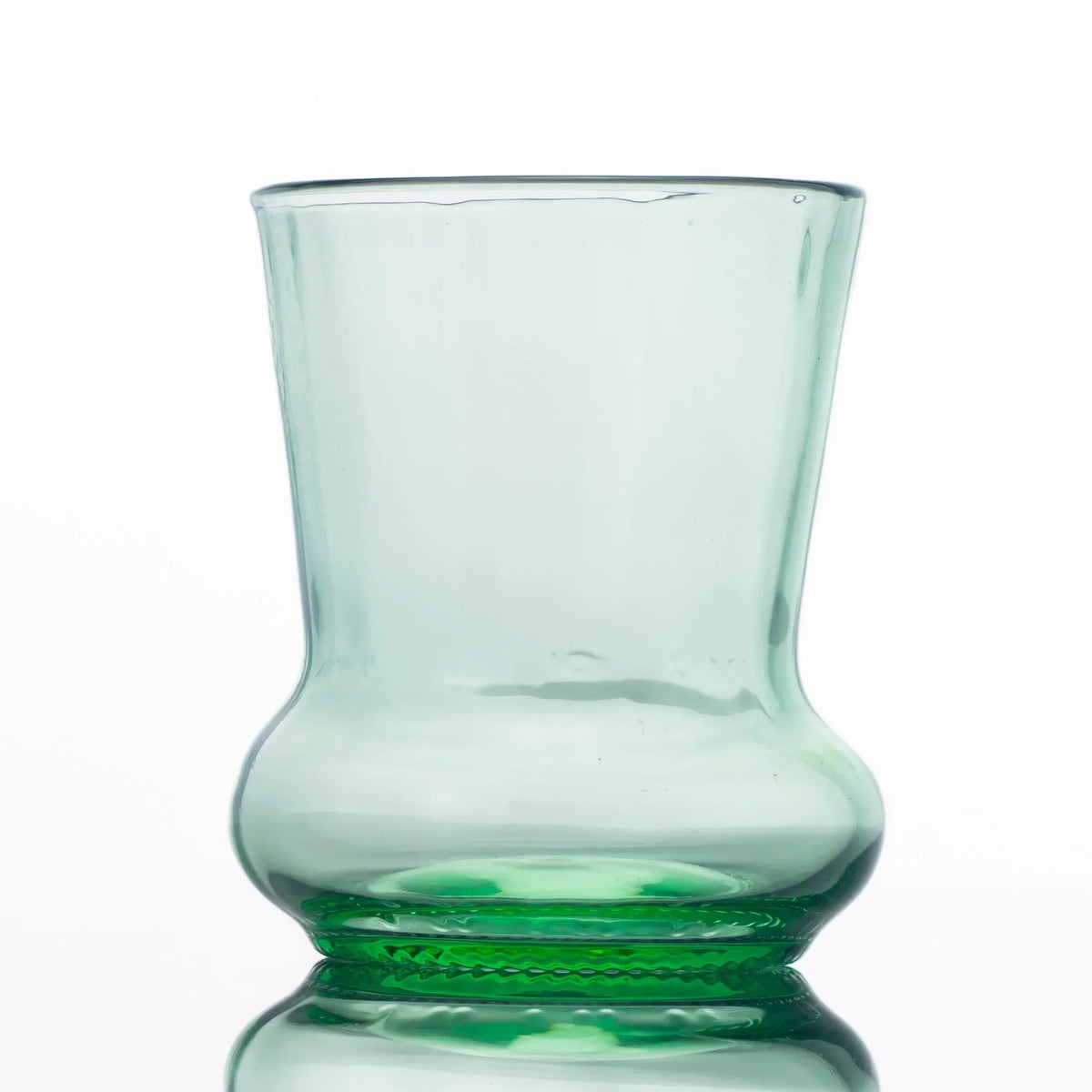 Hand-blown green glass cup with a unique curved design on a white background