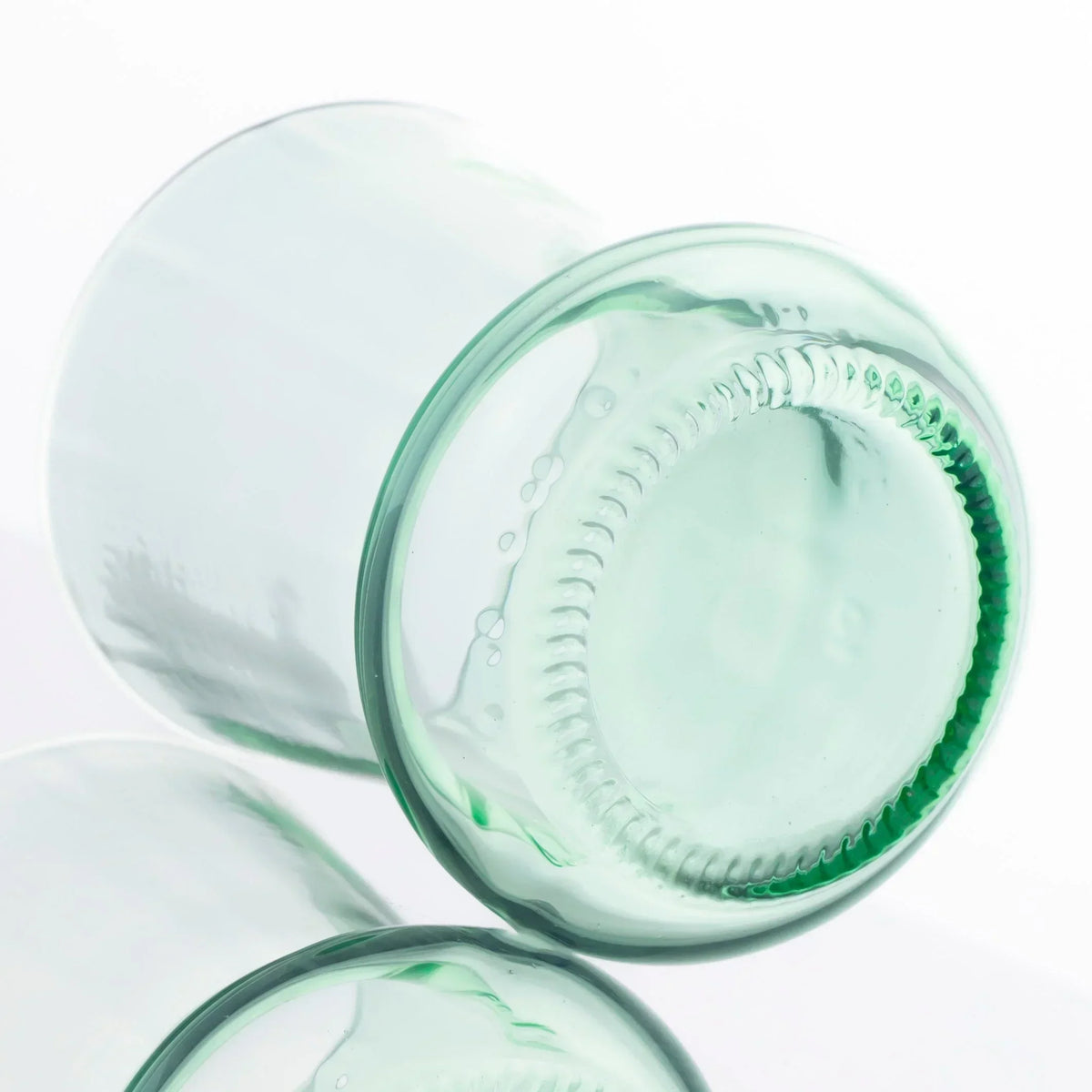 Clear glass cup crafted from upcycled soda bottle with visible bottle base detail