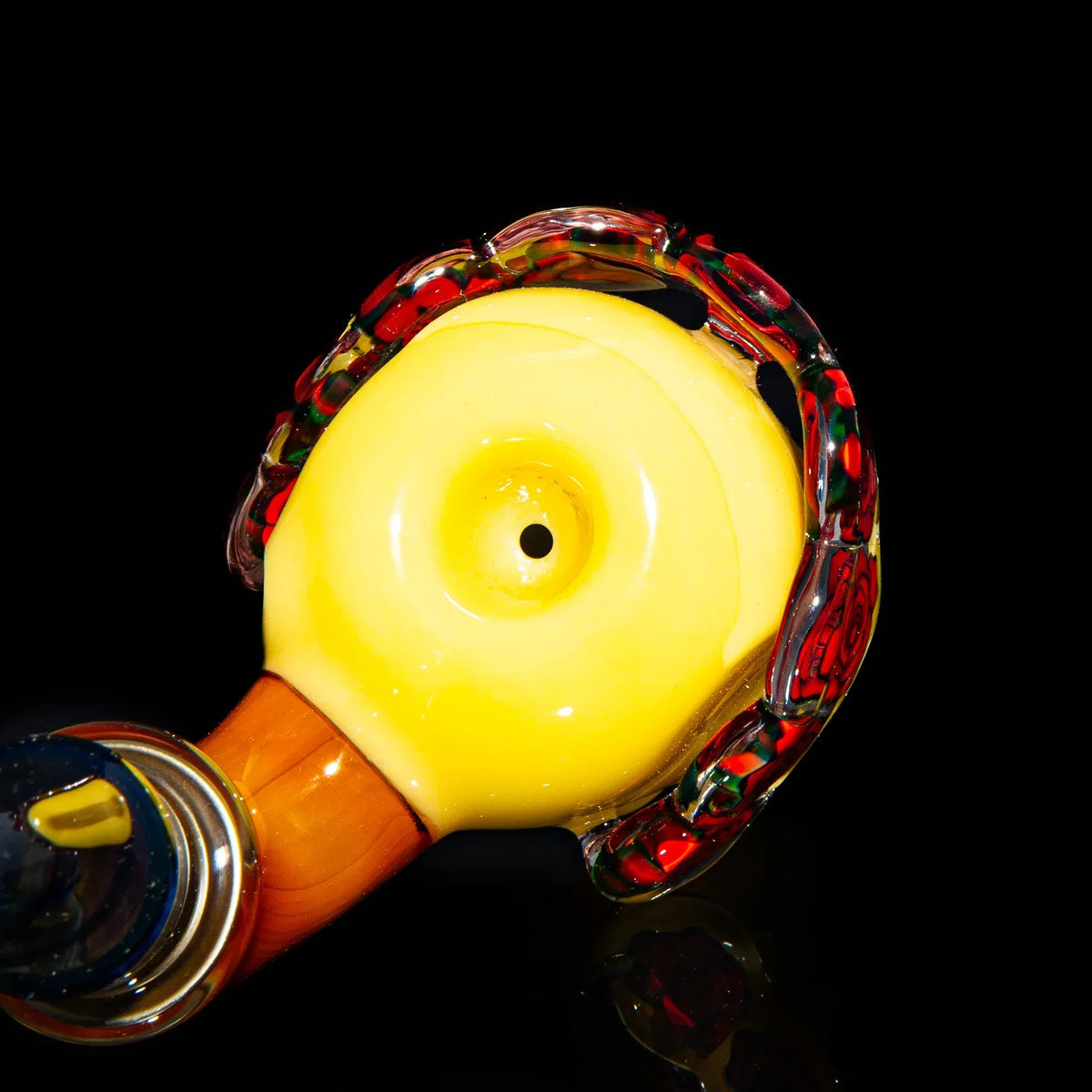 Close-up of artistic yellow glass pipe with colorful accents on black background
