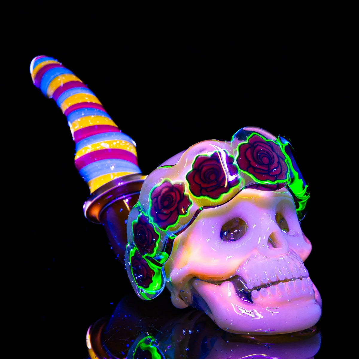 UV reactive glass pipe shaped like a skull with neon floral accents and colorful swirled stem