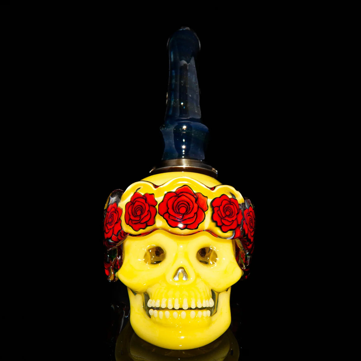 yellow glass skull pipe with red rose crown and dark mouthpiece on black background
