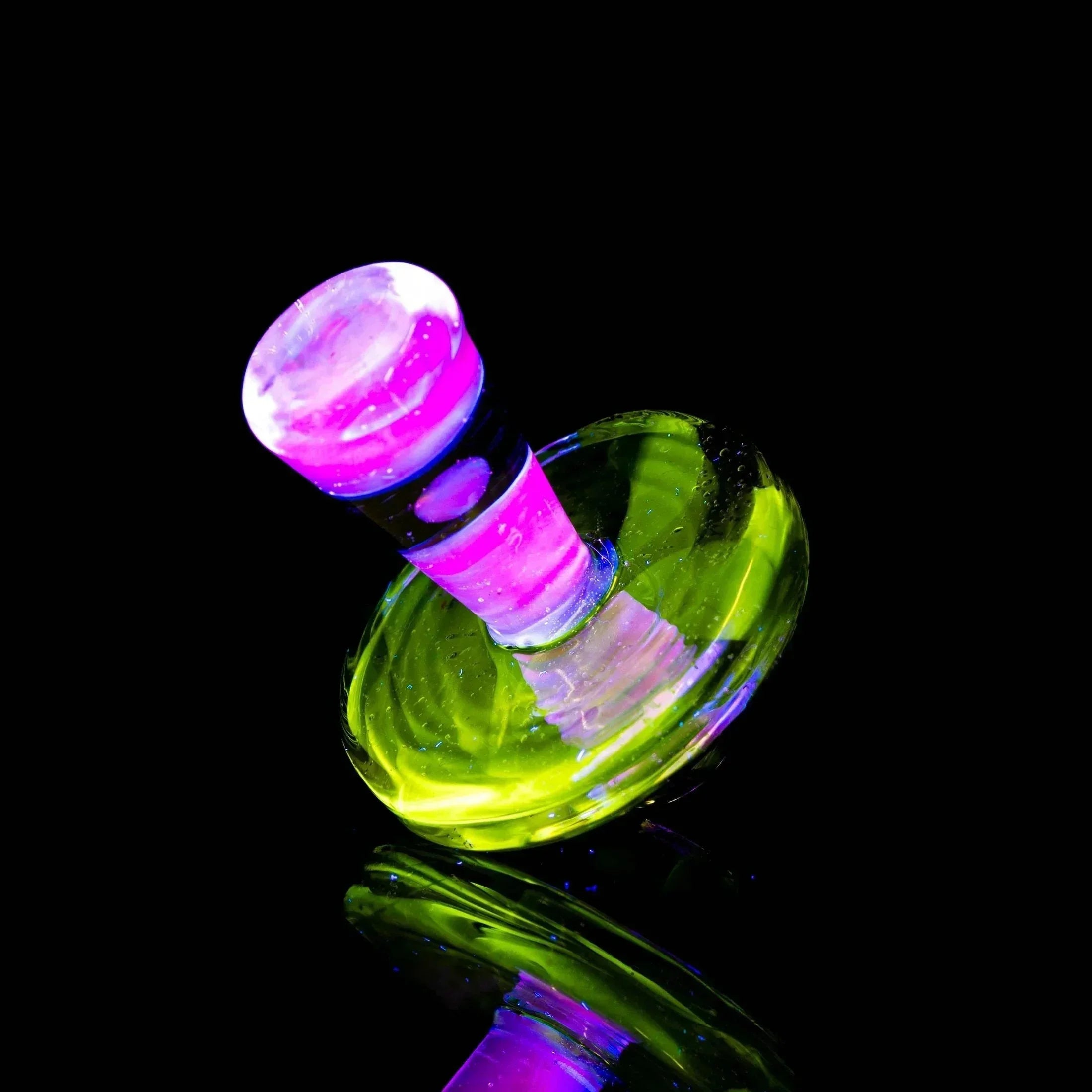 UV-reactive glass carb cap with glowing yellow and purple colors on black background