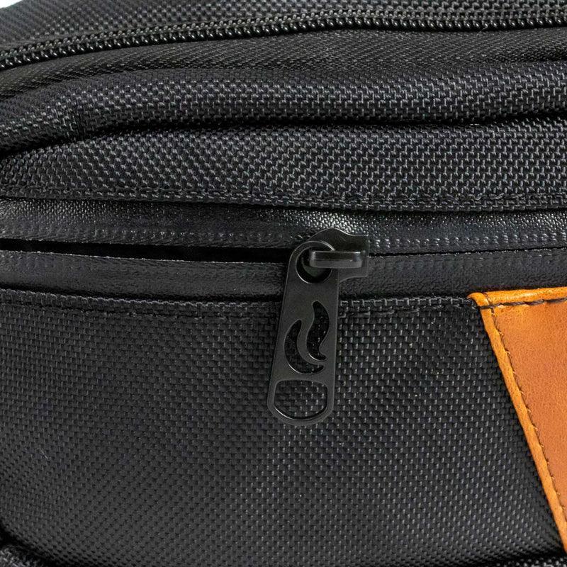 Close-up of black textured hip pack with orange accent and custom zipper pull.