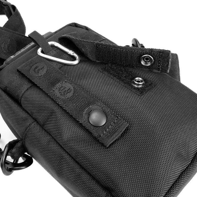 Close-up of black nylon utility pouch with strap, snap buttons, and metal carabiner clip.