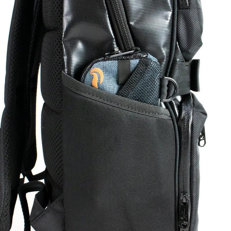 Close-up of black backpack side pocket with zippered pouch and gear inside