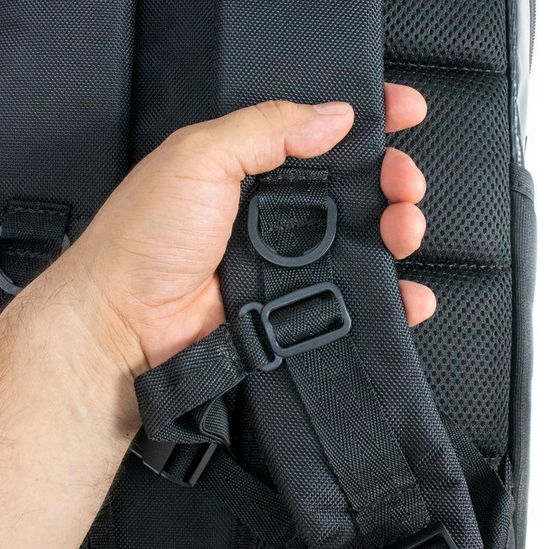 Hand adjusting padded black backpack strap with buckle and D-ring, mesh back panel visible