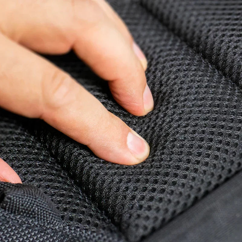 Hand pressing into black mesh padded fabric, showing cushion texture detail