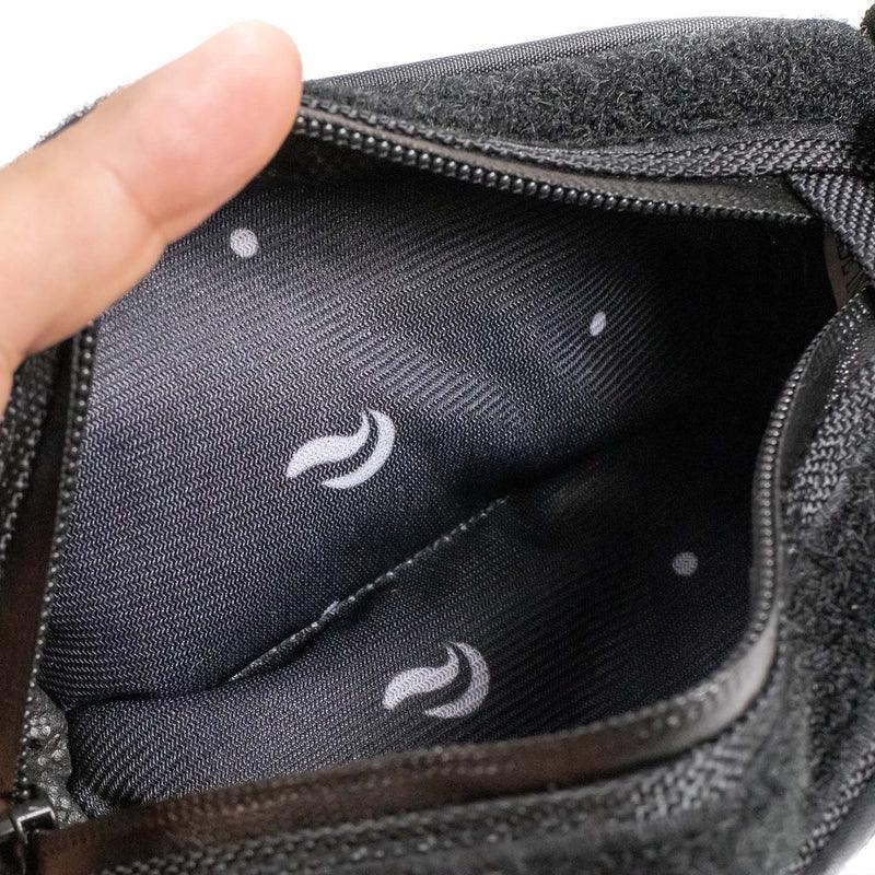 Closeup of an open black travel pouch with zippered closure and patterned fabric lining