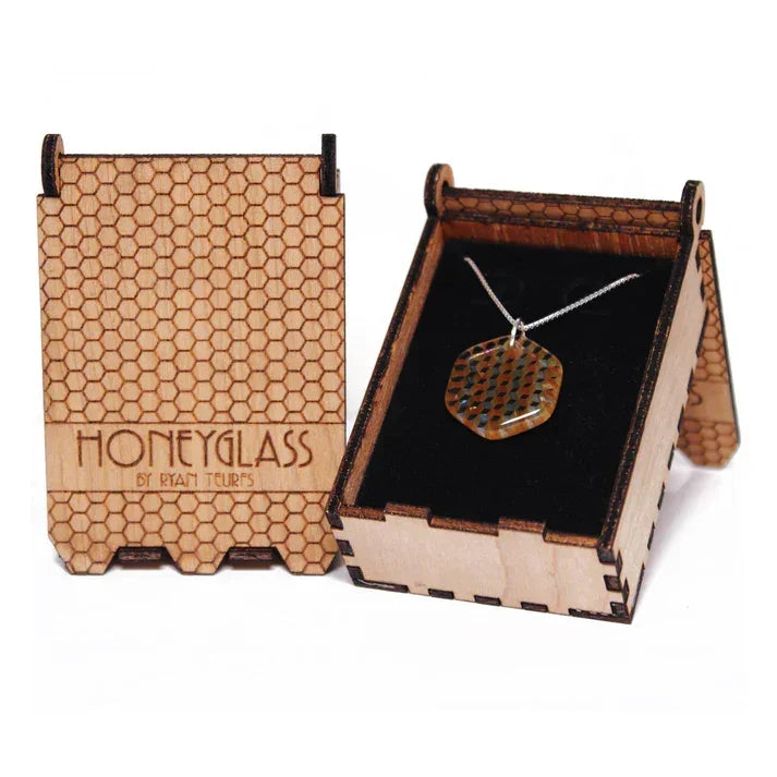 Striped hexagon honey glass necklace displayed in a laser-etched wooden box with honeycomb pattern.