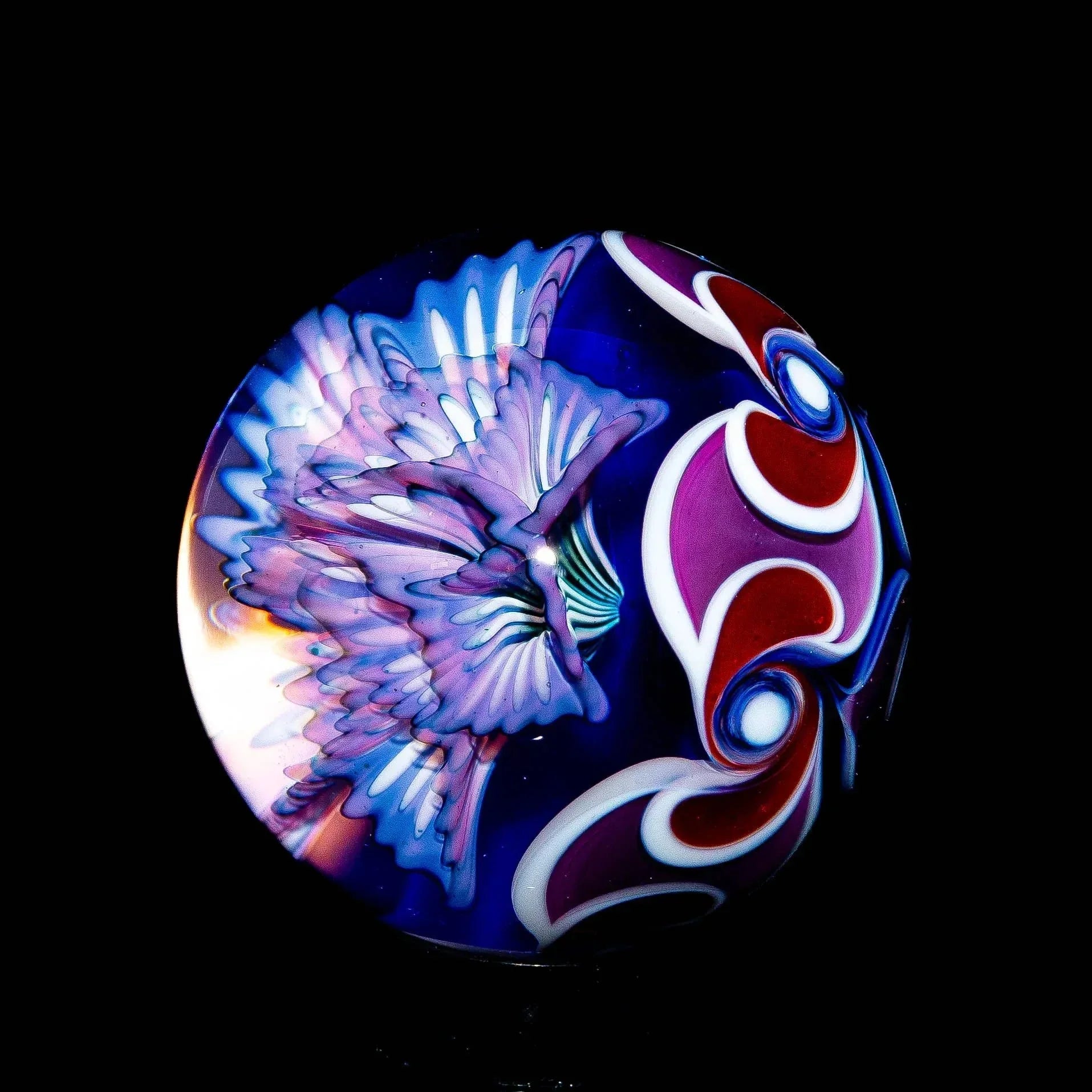 Colorful glass marble with intricate purple, red, and white patterns on a black background