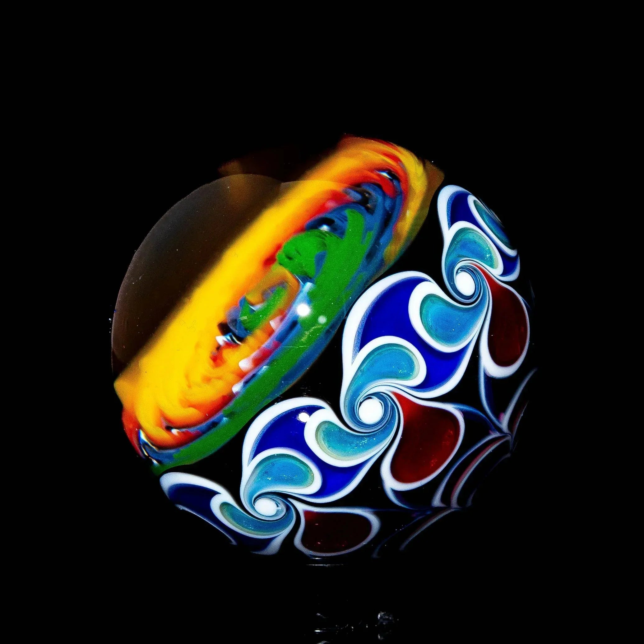 Colorful wig wag glass marble with vibrant swirls and flame-like designs on black background